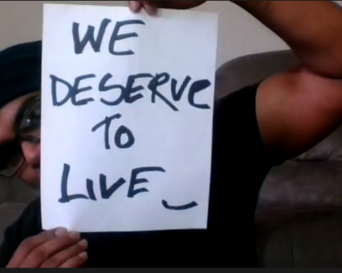 Screenshot of restaurant worker, Md Masud Rana, holding a placard reading "WE DESERVE TO LIVE.", COVID-19, benefits, employment
