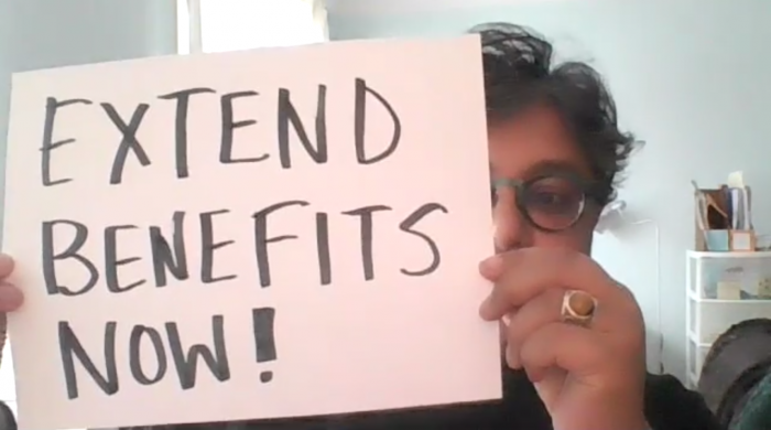 WAC executive director, Deena Ladd, holds a placard reading "EXTEND BENEFITS NOW.", benefits, employment