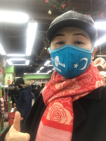 Photo of Sheng Xue wearing a face mask with a message supporting Uyghurs, who are targetted by China's transnational repression campaign.