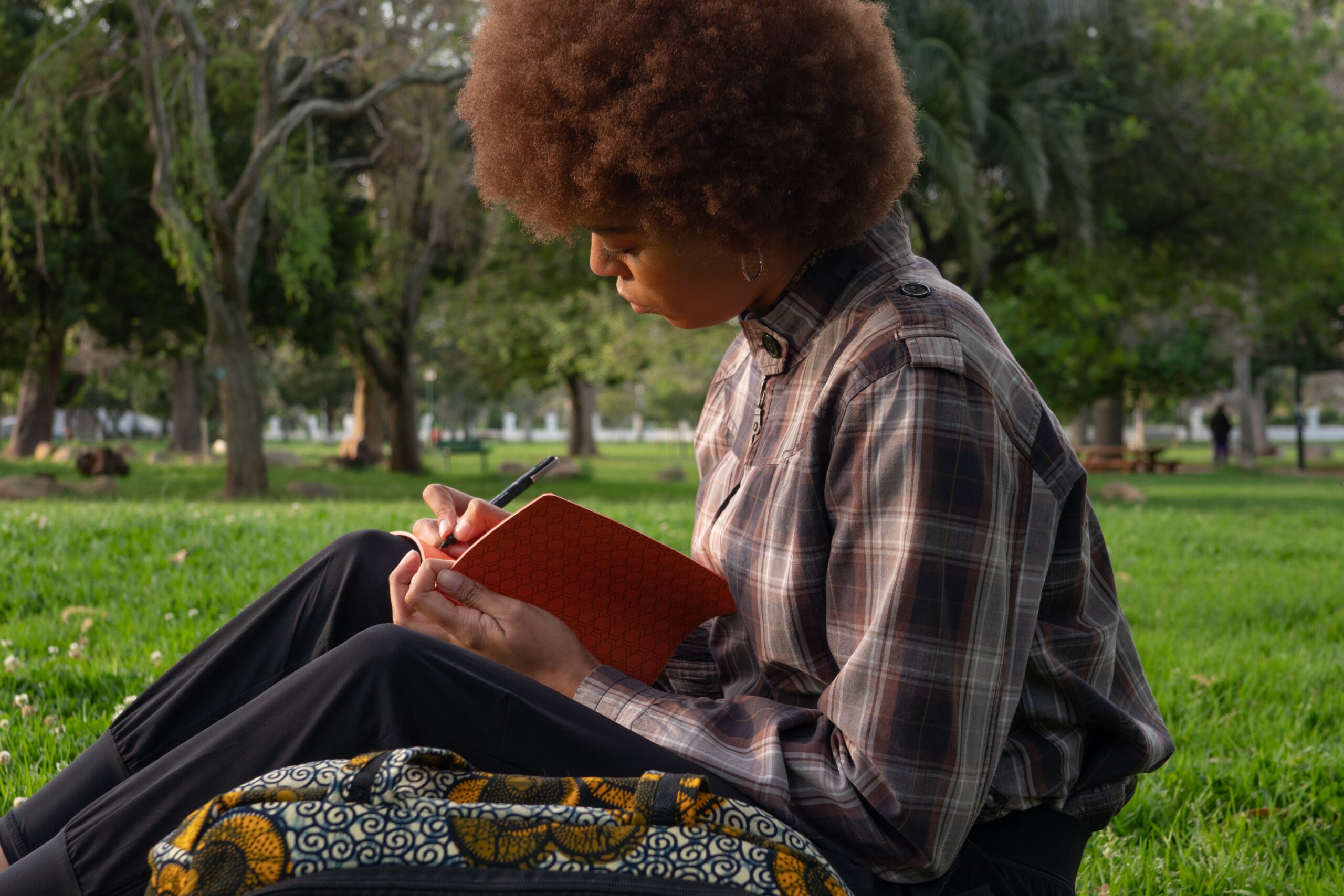 Une jeune fille écrit dans un cahier dans un parc