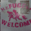 PhPhoto of a sign that reads "Refugees Welcome" and a graphic representation of people running.
