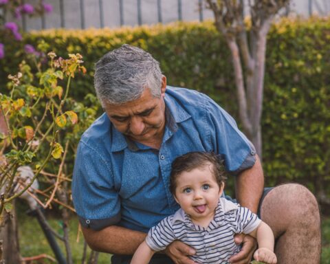 A grandfather holding his grandson in a backyard. Family ties in Canada is often cited by authorities as a reason to deny entry to family members of new Canadians.