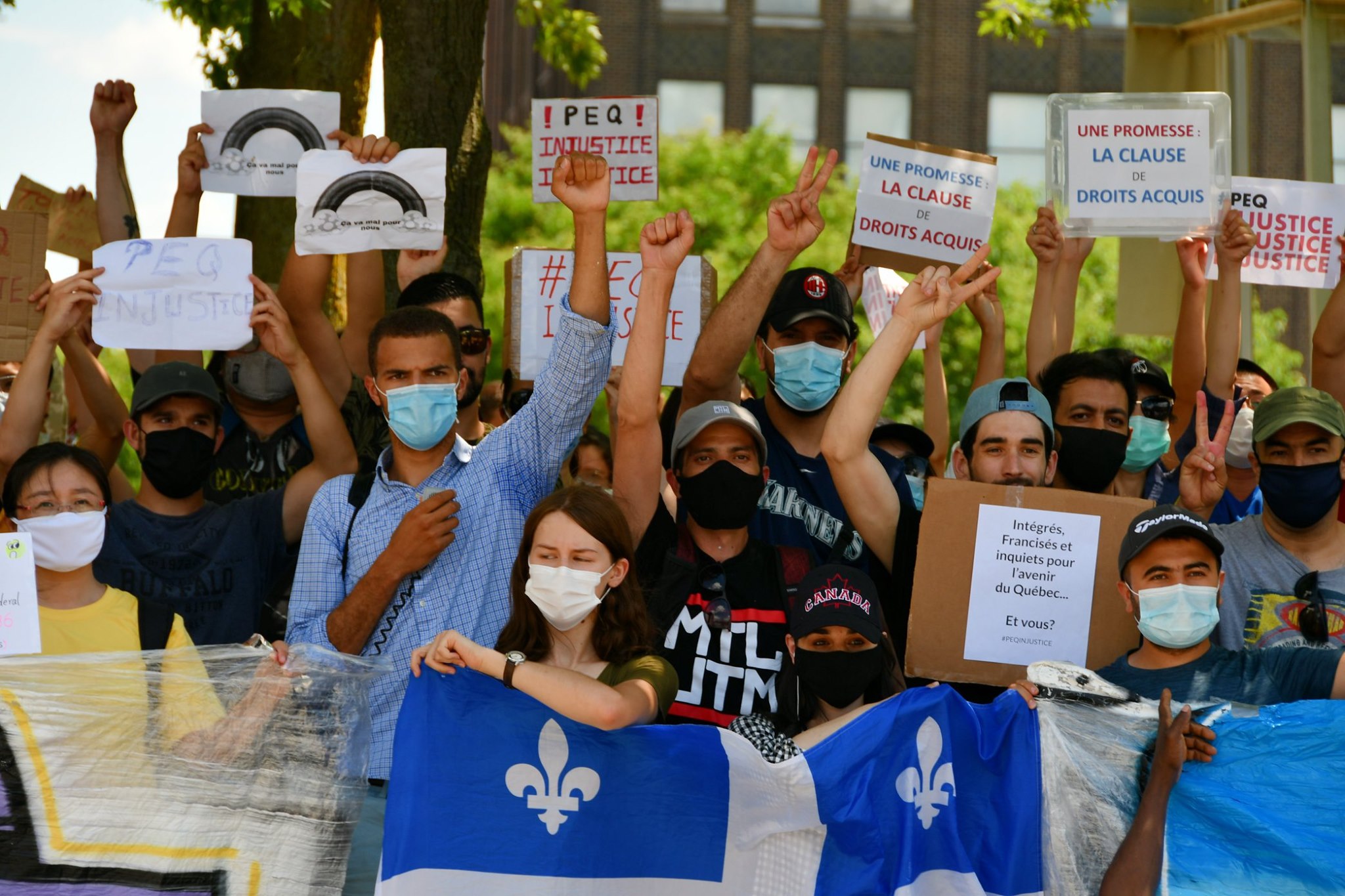 Des manifestants à Montréal soutenant un drapeau du Québec et des pancartes