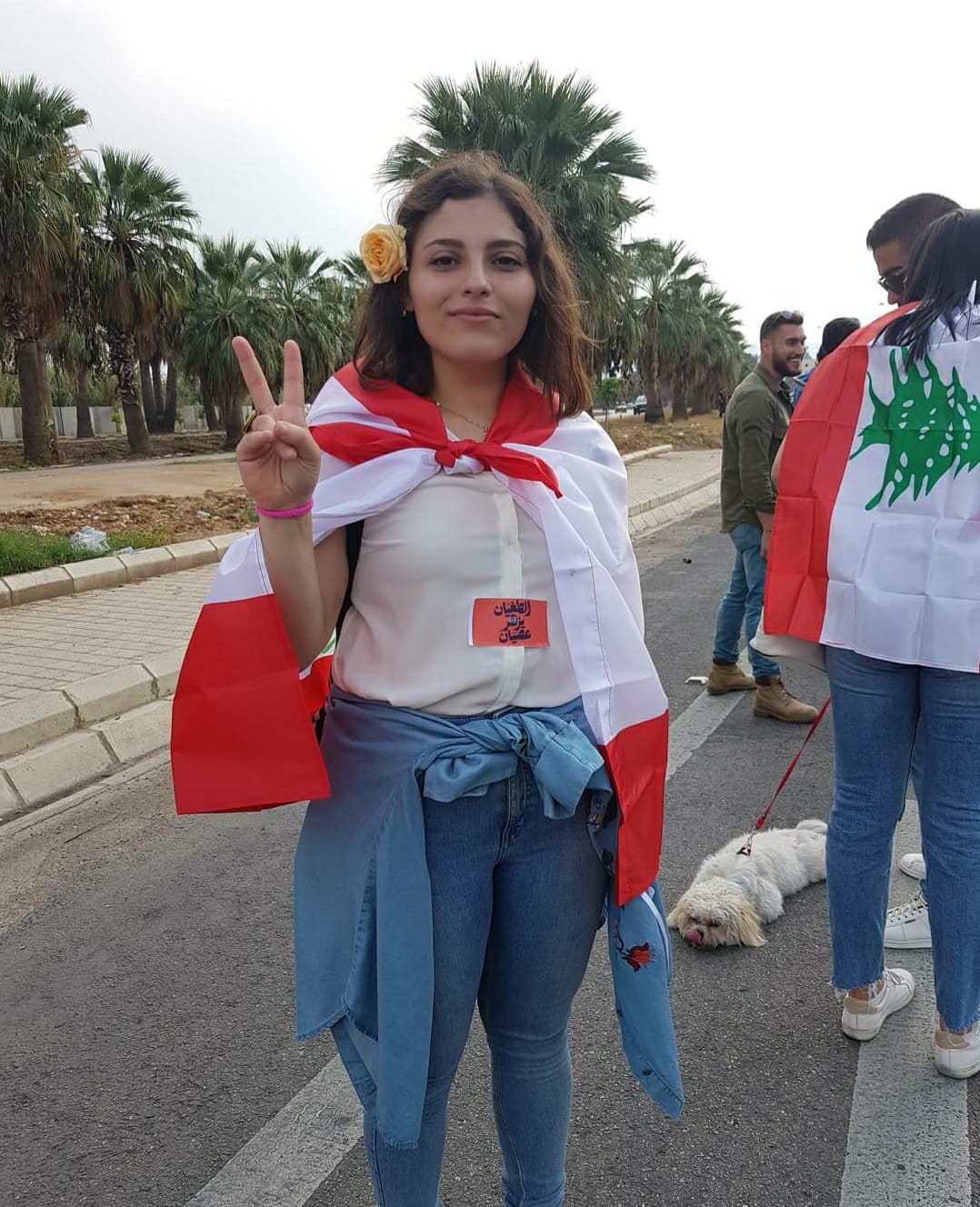 Une jeune femme pose avec un drapeau libanais et un signe de la paix