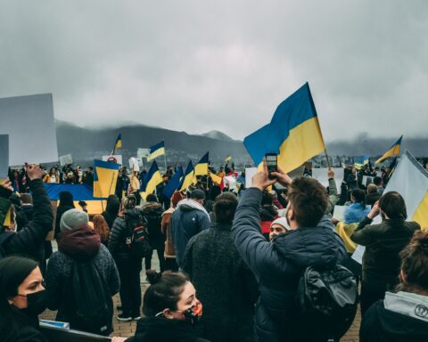 A crowd of people standing with Ukrainian flags and signs at a protest for Ukraine in Vancouver, B.C.