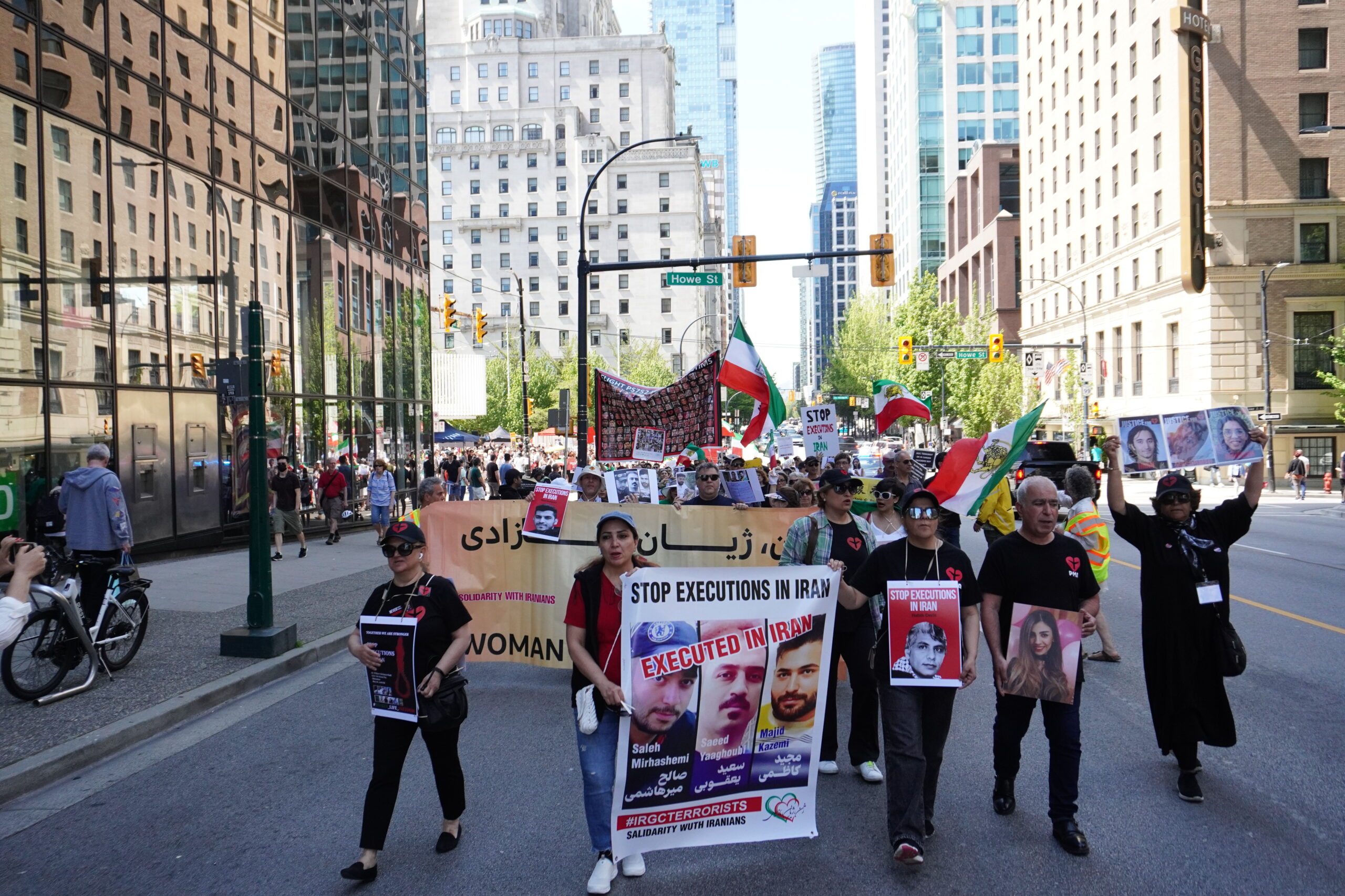 Protesters march in Vancouver on May 20 holding signs that condemn unlawful executions in Iran