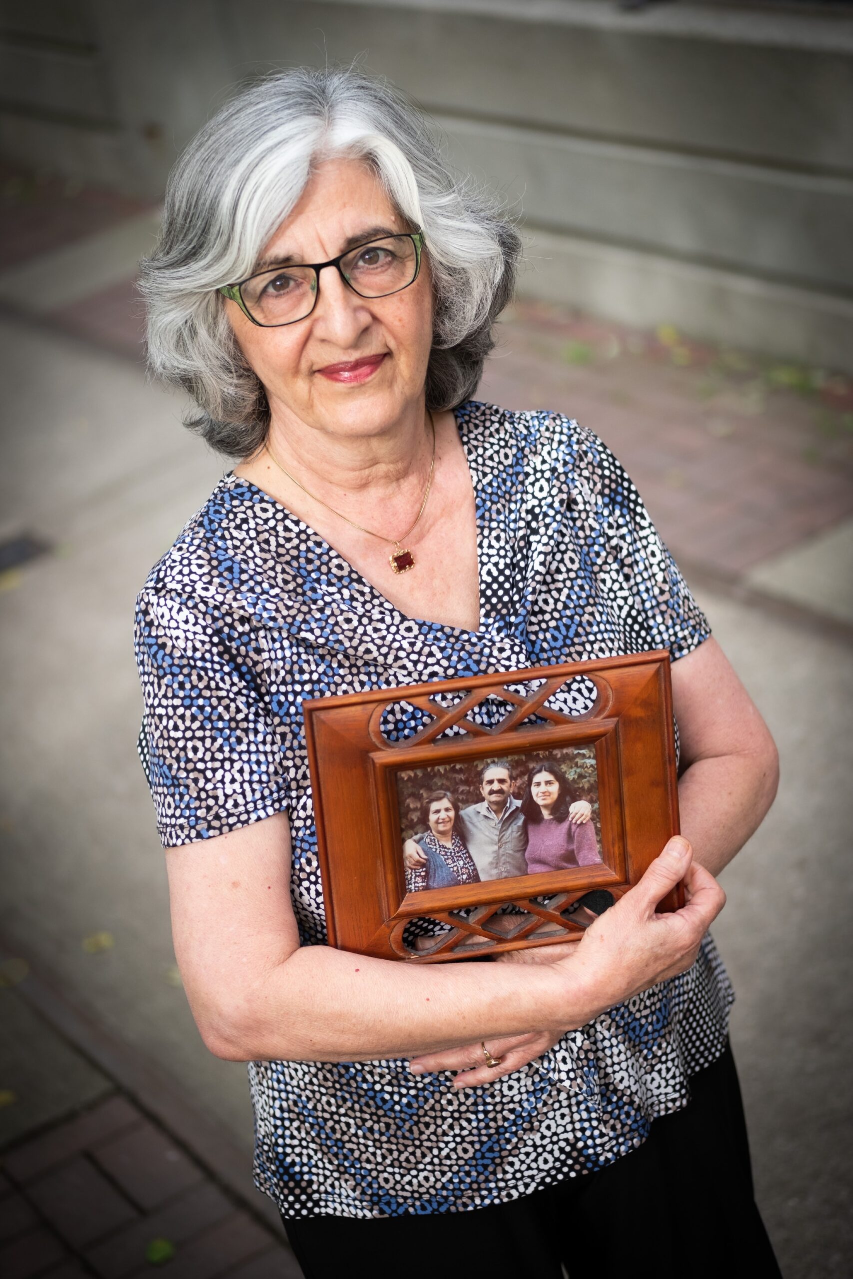 Nahid Mazloum, holds up a portrait of her mother Ezzat Janami Eshraghi, sister, Roya Eshraghi and her father, Enayatollah Eshraghi all of whom were executed in June 1983 in Iran for their belief in the Baha’i faith