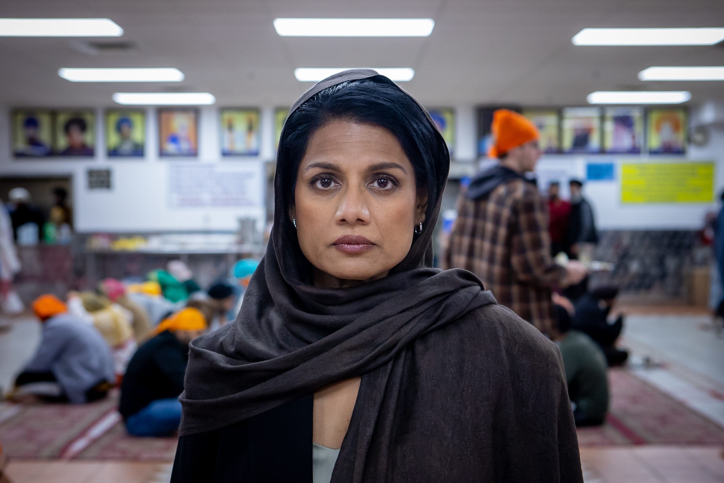 A woman wearing a black headscarf and patterned clothing looks toward the camera in a still from the film Calorie.
