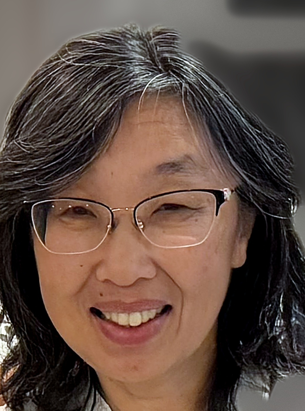 Close-up portrait of immigration lawyer Mary Lam smiling and wearing glasses.