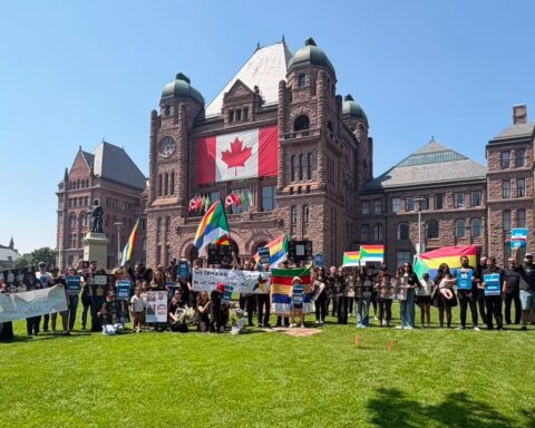 Druze community members hold flags, signs and photographs during a rally outside the Ontario legislature at Queen’s Park in Toronto.