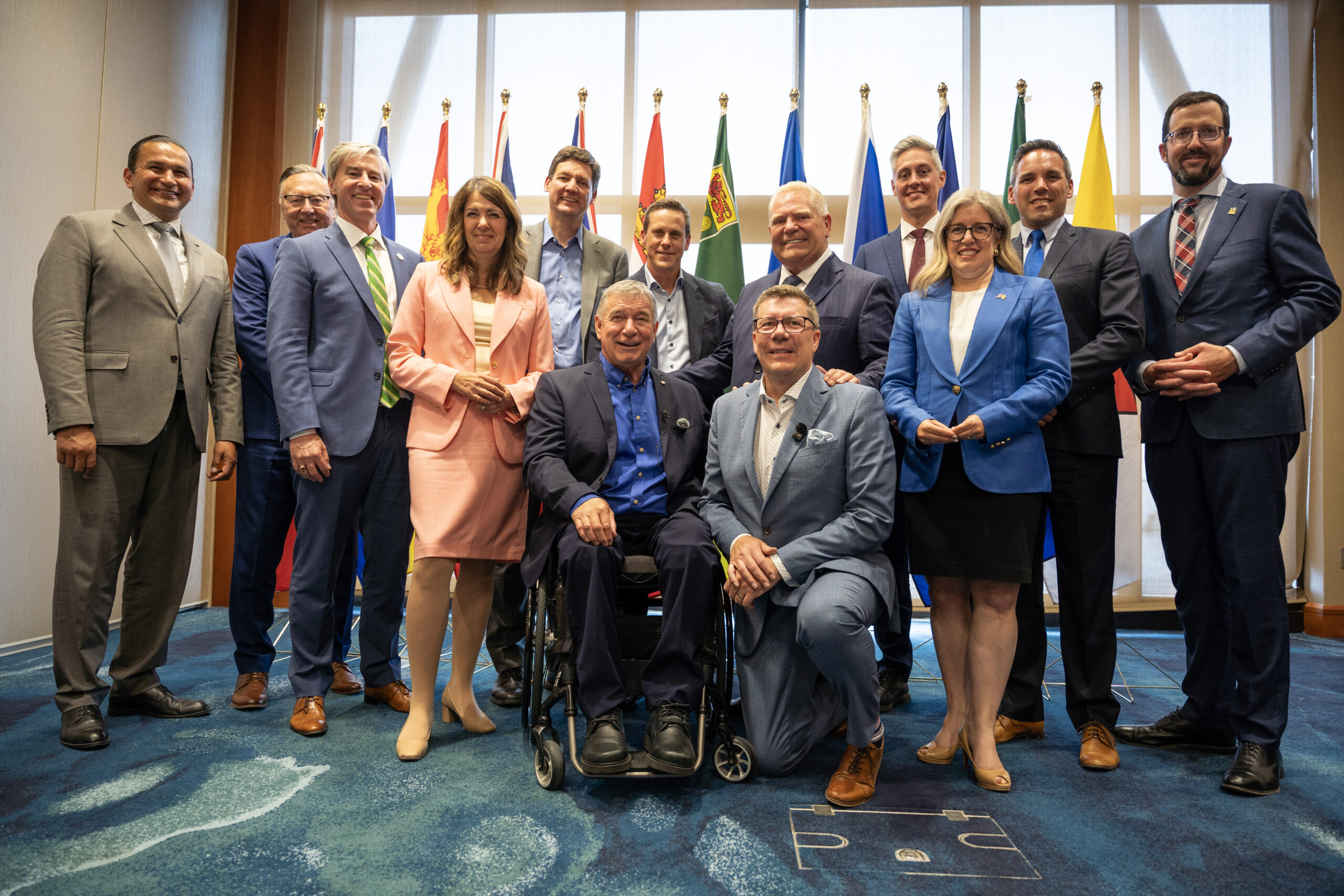 Canada's provincial and territorial premiers pose for a group photo in front of provincial and territorial flags at the Council of the Federation meeting in Charlottetown, PEI.