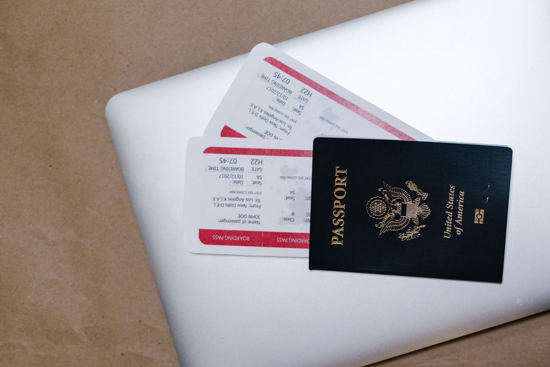A passport and travel tickets placed on top of a laptop.