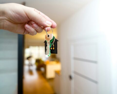Close-up of a hand holding house keys at the entrance of a home, symbolizing newcomer homeownership in Canada.