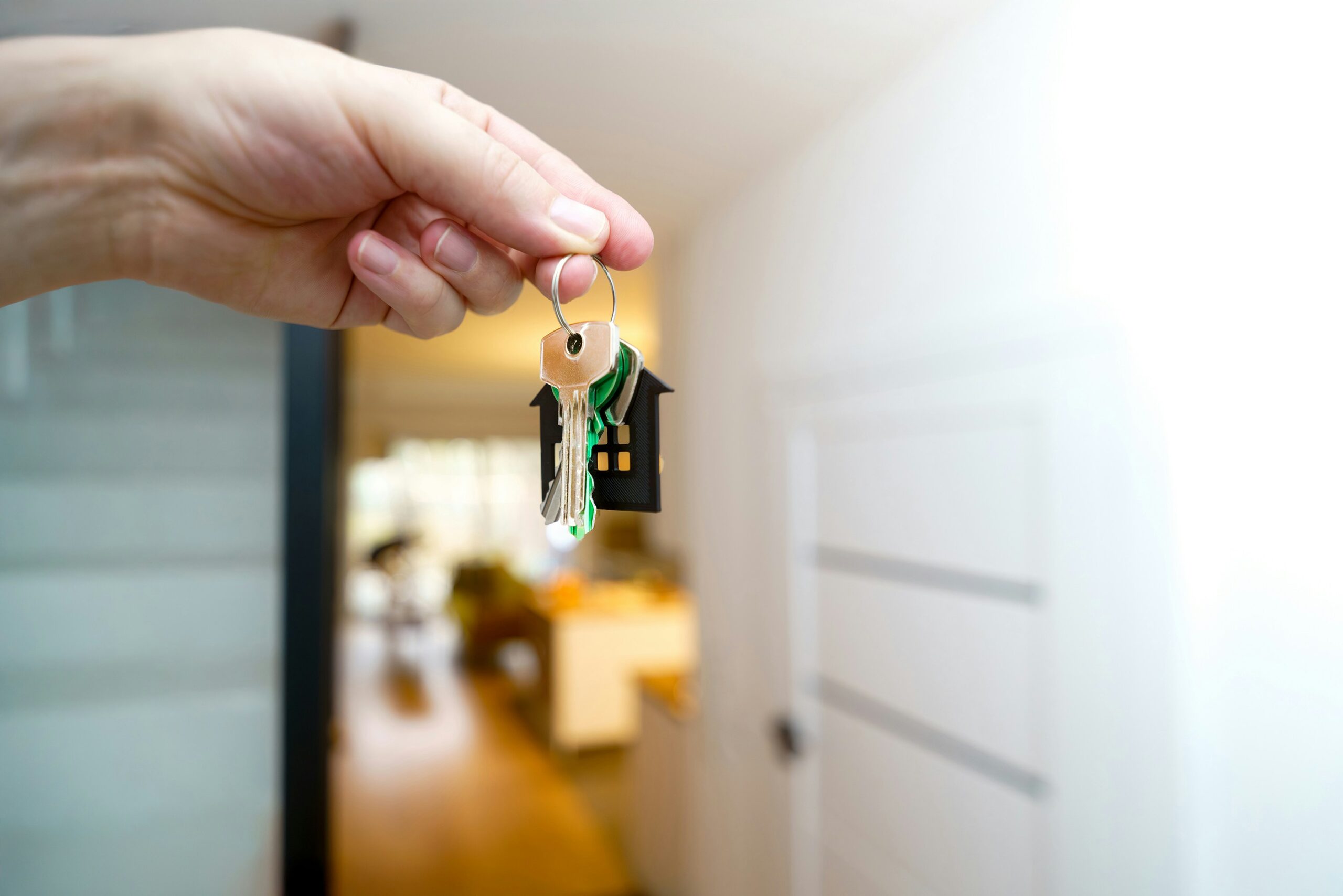 Close-up of a hand holding house keys at the entrance of a home, symbolizing newcomer homeownership in Canada.