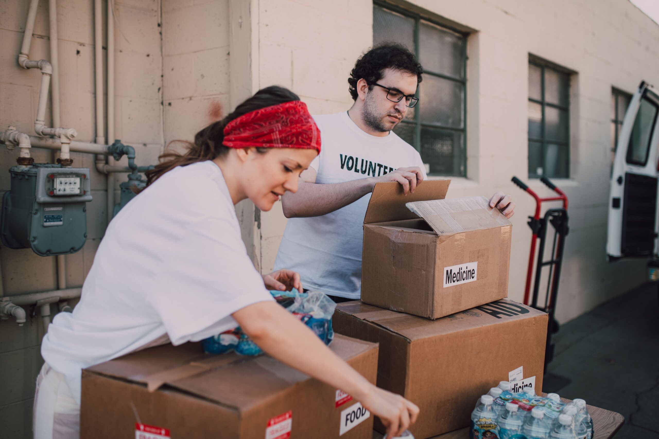 A man and a woman pack donated goods into cardboard boxes as part of community relief efforts.